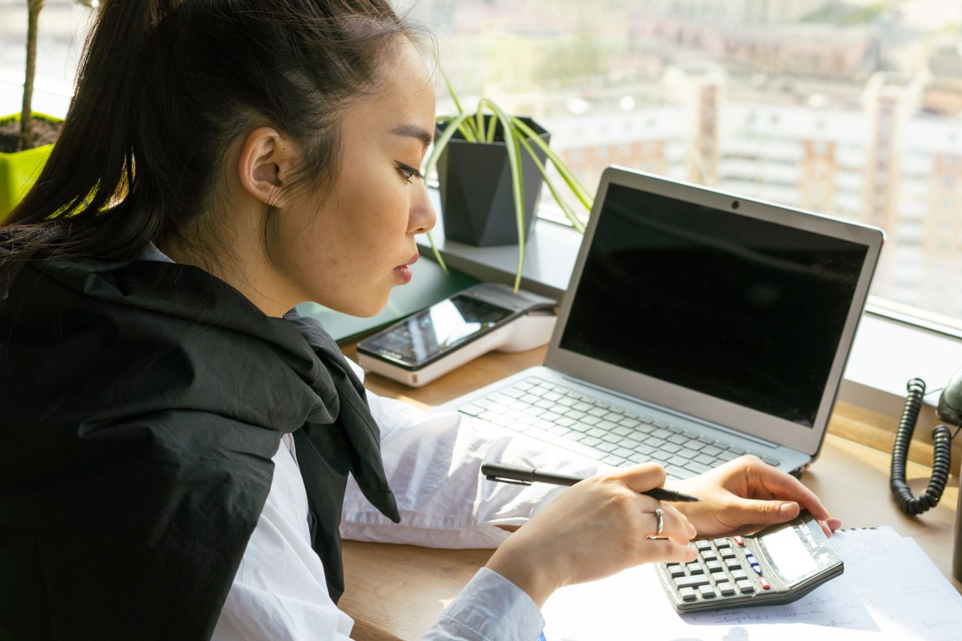 A finance officer working with a calculator and a laptop