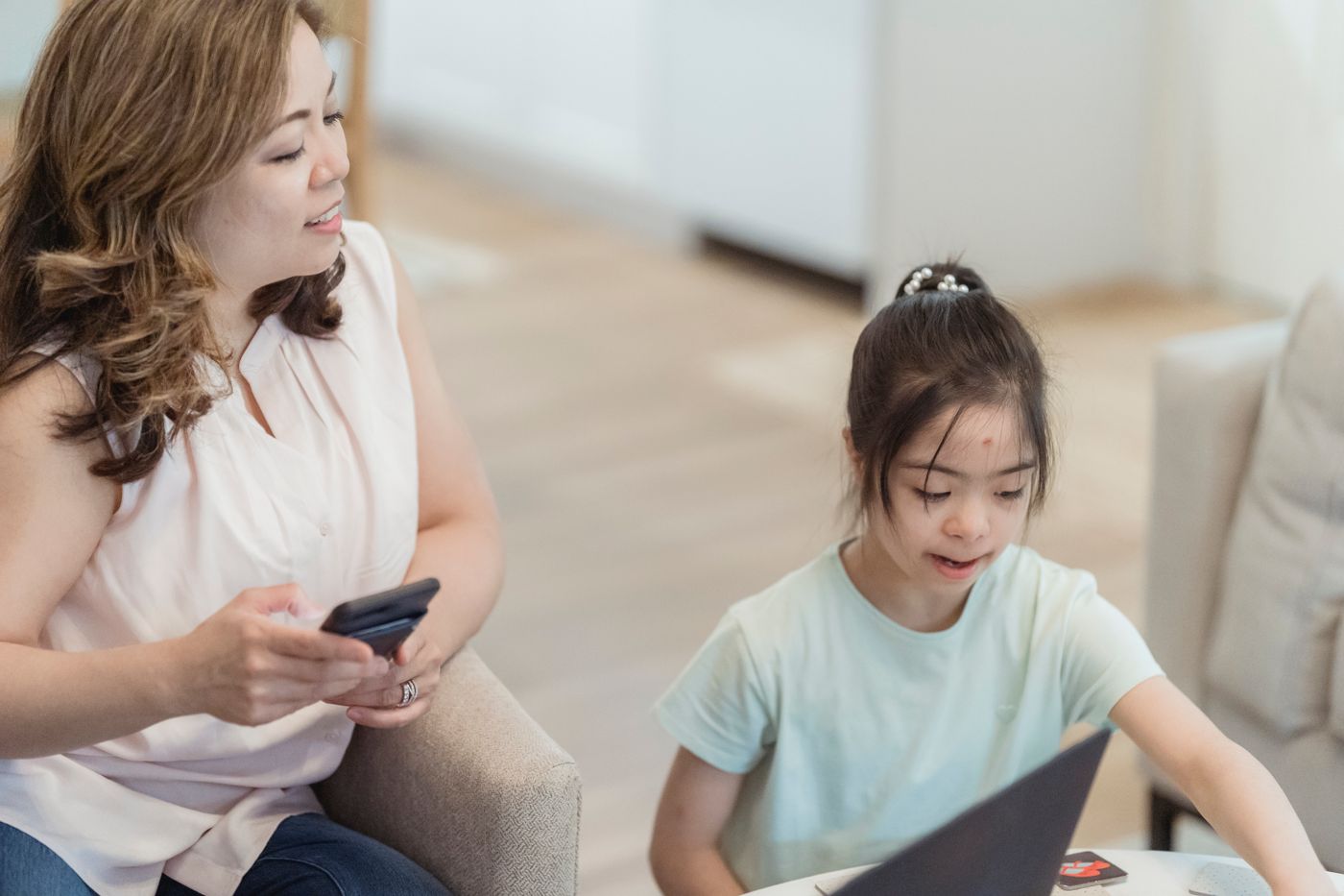 A parent using a phone while a child does homework